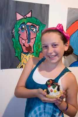 Standing in front of her self-portrait, Devin Ruskin, 11, of Lake Worth shows off a ceramic cupcake. (Photo by Katie Deits)