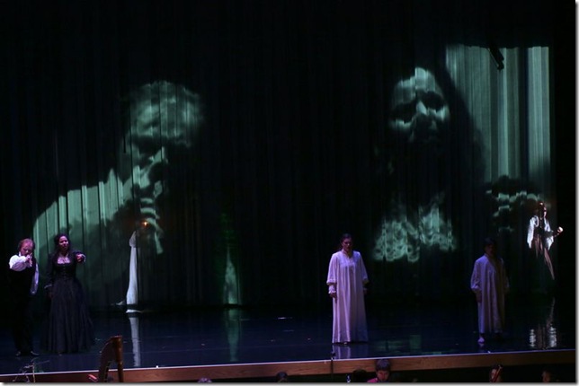 Kyle Erdos-Knapp and Shirin Eskandani, at left and projected on the stage as the ghosts Quint and Jessel in The Turn of the Screw.